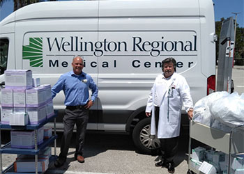 James Watson, supply chain director at Wellington Regional Medical Center, picks up medical supplies from Ed Willey, dean of Health Sciences at PBSC.